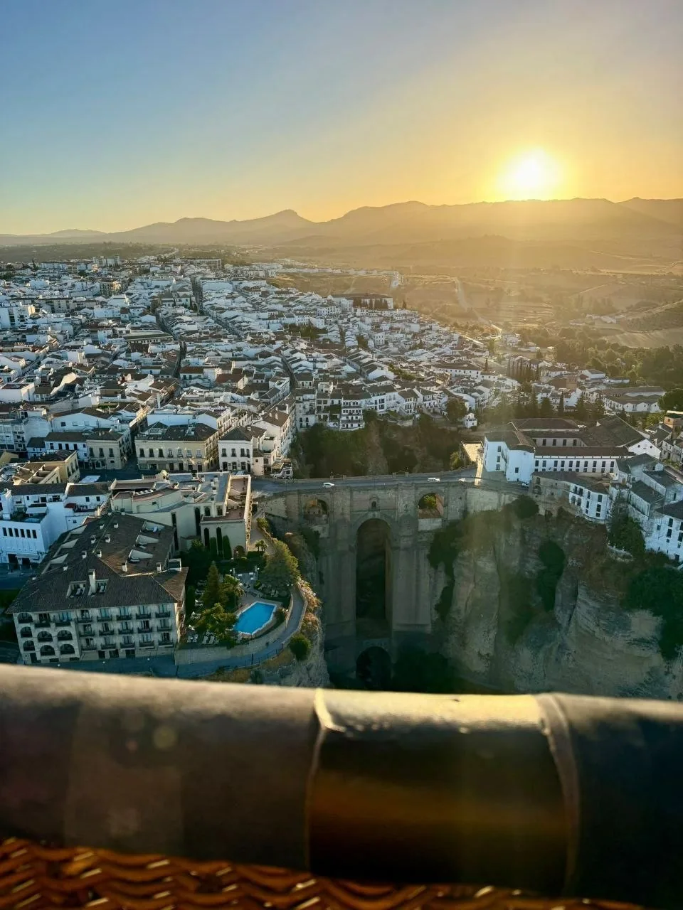 Vista aérea de Ronda al amanecer: el Puente Nuevo sobre el Tajo, el casco blanco de la ciudad y la sierra al fondo