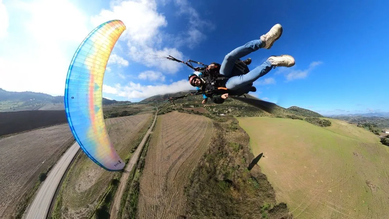 Parapente volando sobre la sierra, con el paisaje al fondo