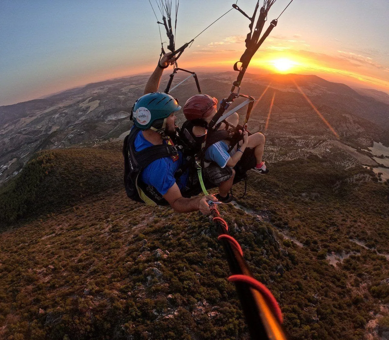 Vuelo en parapente biplaza al atardecer sobre la sierra, sereno y bajo control del piloto