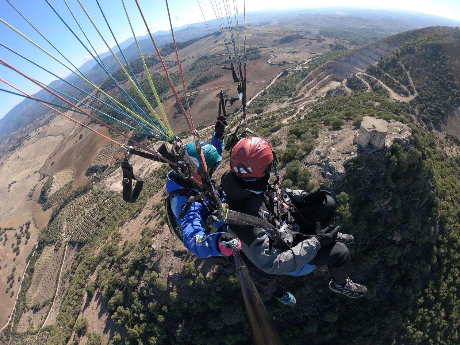 Vuelo en parapente biplaza: pasajero y piloto sentados juntos, volando en calma sobre la sierra